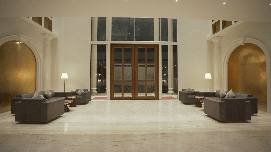 Full view shot of lavish lobby at  Pride Resort Rajkot with a large entrance door elegant decor and sofas.