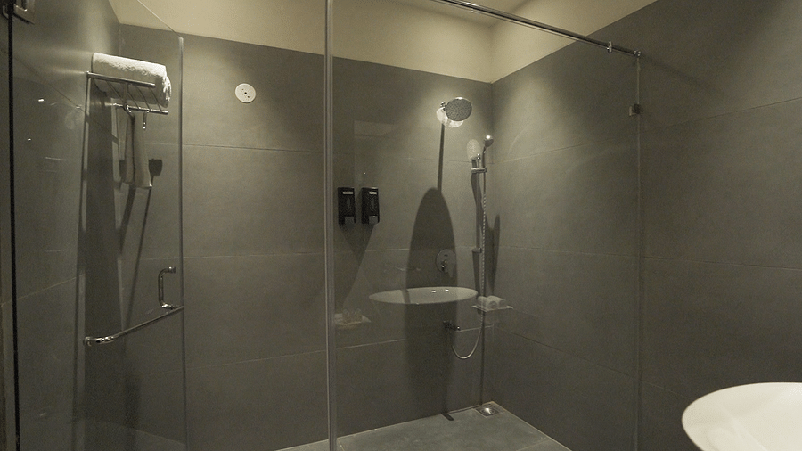 A bathroom with a glass-enclosed shower, a sink, and a towel rack  - Pride Resort, Rajkot