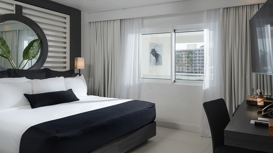 An image of our accommodation in Montego Bay with a comfy bed and a work desk - S Hotel Montego Bay, Jamaica