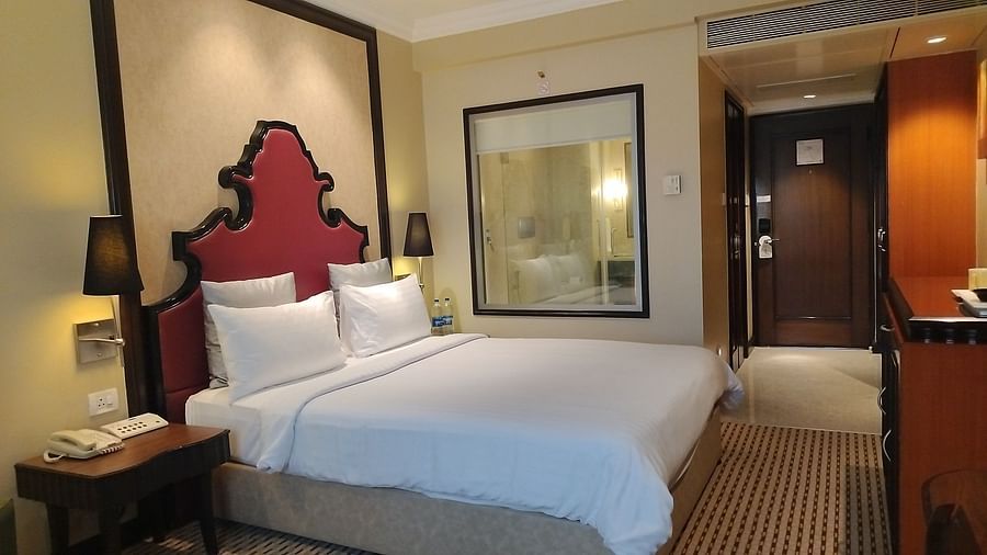  Hotel guest room with a large bed, bedside lamps, framed artwork, and a full-length mirror.
