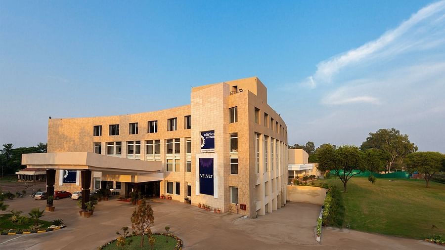 Facade view of Clarks Exotica with trees, and grass surrounding the building.