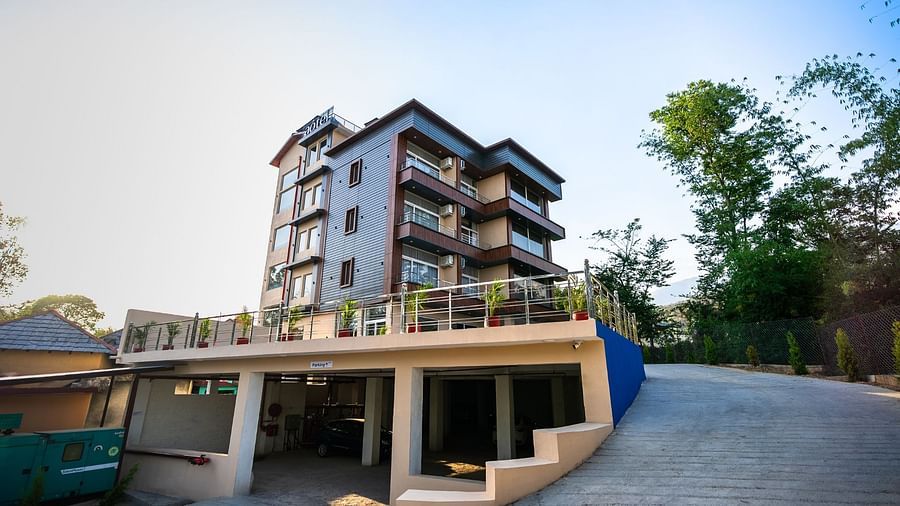 Low-angle facade view of the hotel, highlighting the architecture and surrounding trees.