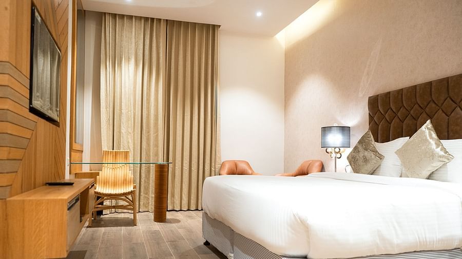 Super Deluxe Room featuring a plush bed with a lamp next to it mounted on a nightstand and a sleek LED TV in front of the bed