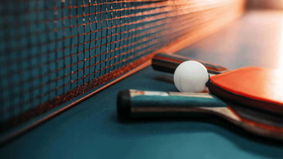 table tennis racket and a ball kept by a net