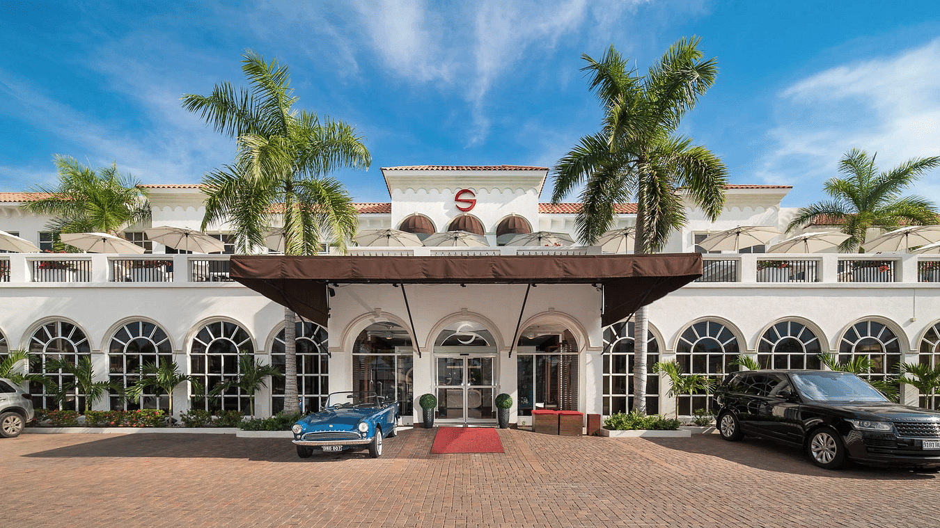 A hotel entrance seen during a sunny day with cars parked in front of it - S Hotels, Jamaica