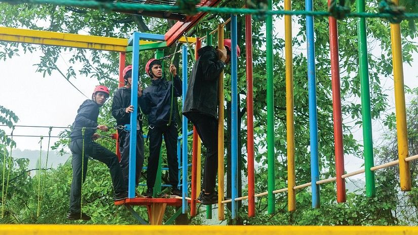 a group of teenagers on a bridge course outdoors during daytime