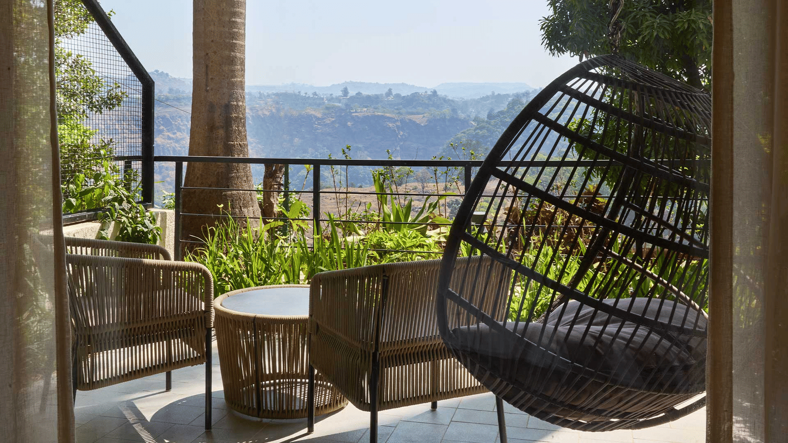 A beautiful veranda with a swing and chairs overlooking beautiful mountain views at Athiva Resorts & Spa, Khandala | Nature resorts near Khandala are ideal for weekend trips