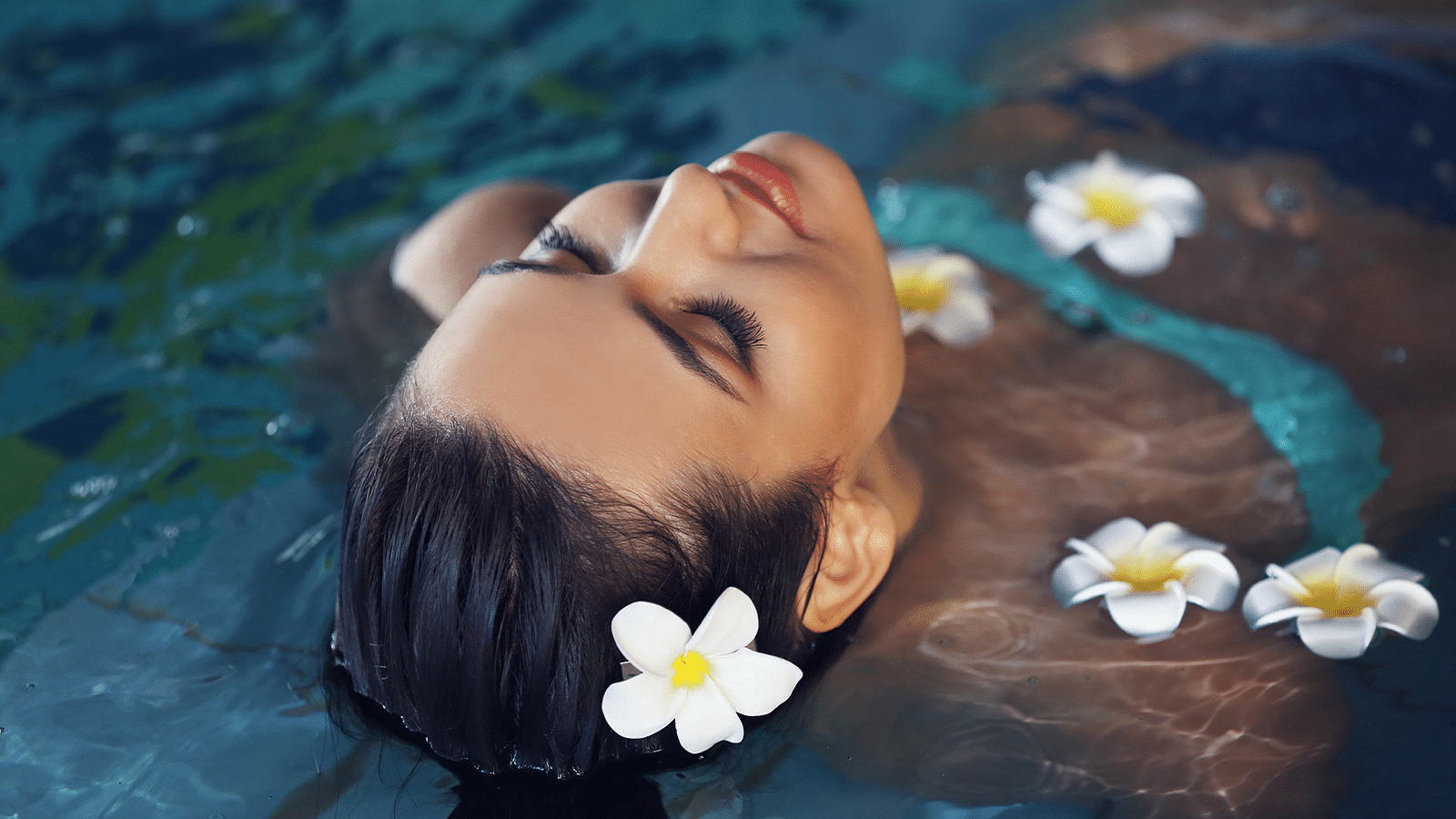 Woman floating serenely in water with flowers, capturing a moment of peacefulness