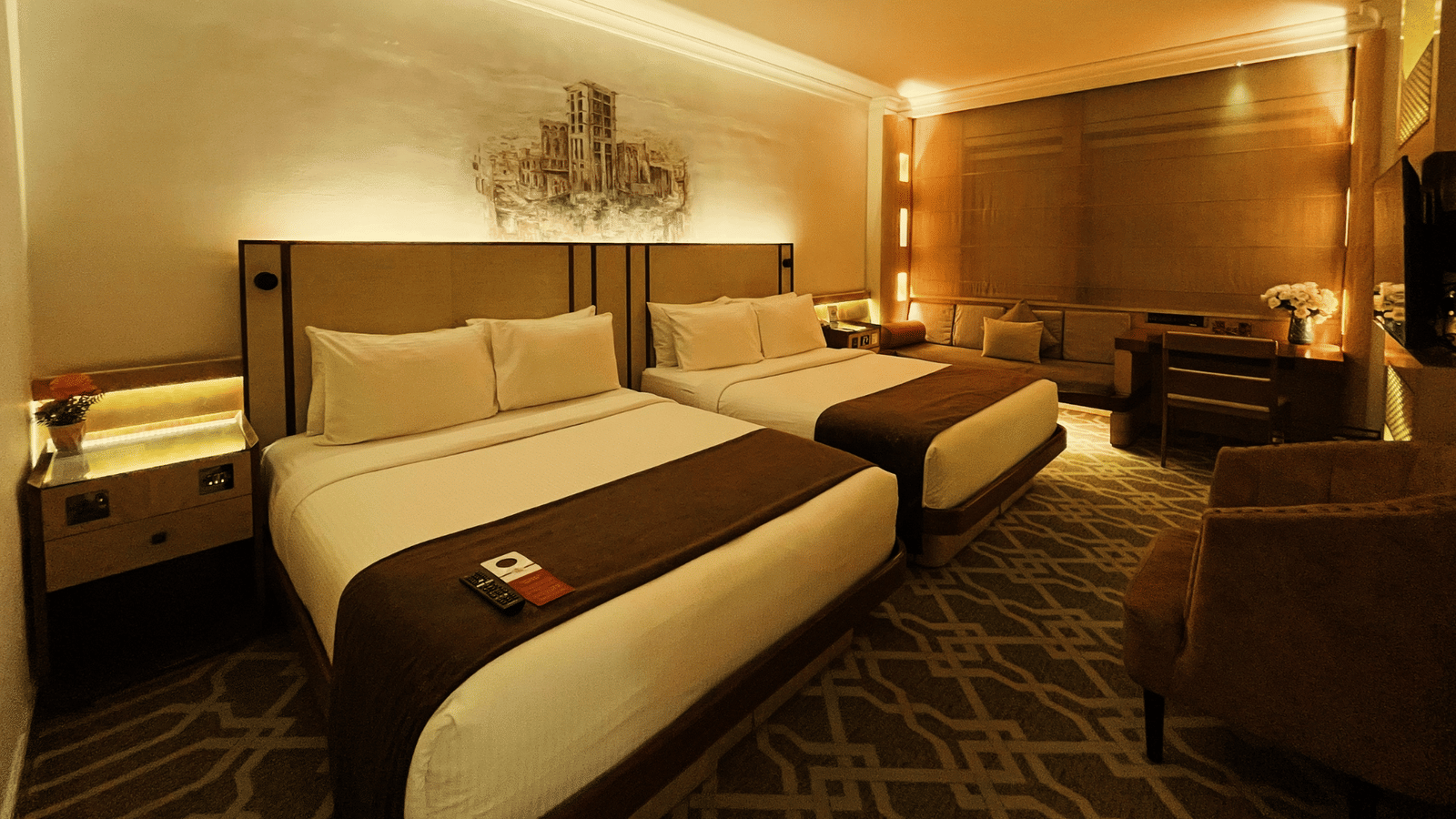 Wide shot showing two twin beds and a bedside table in a room at Marco Polo Hotel.