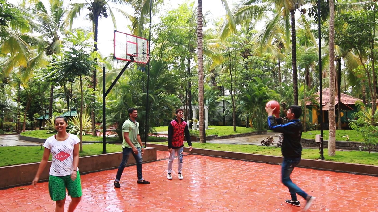 Image of four people playing basketball with trees in the background at Parampara Resort & Spa, Kushalnagar.