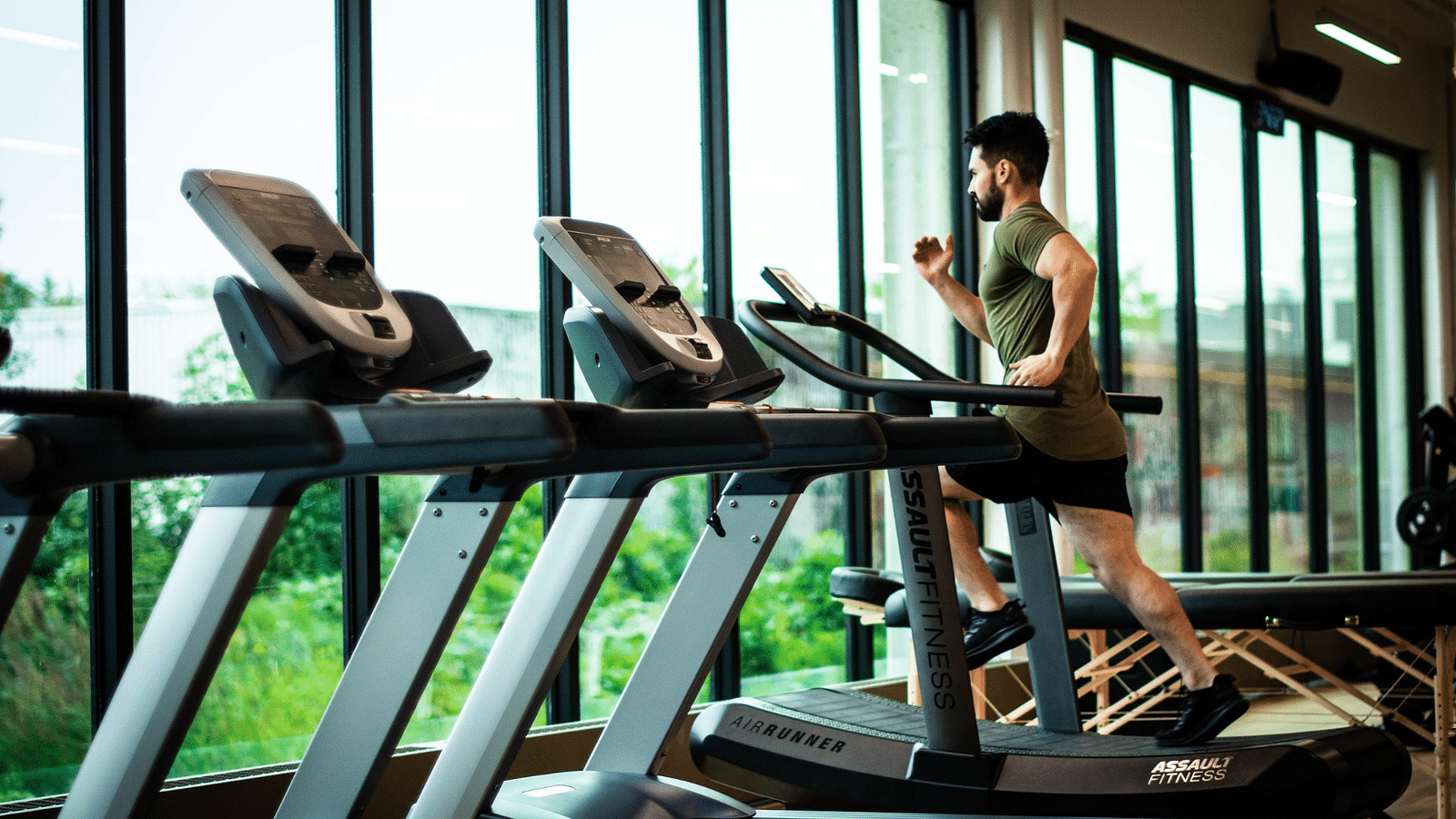 a person running on a treadmill with other treadmills next to him inside the fitness centre - Rhythm Gurugram