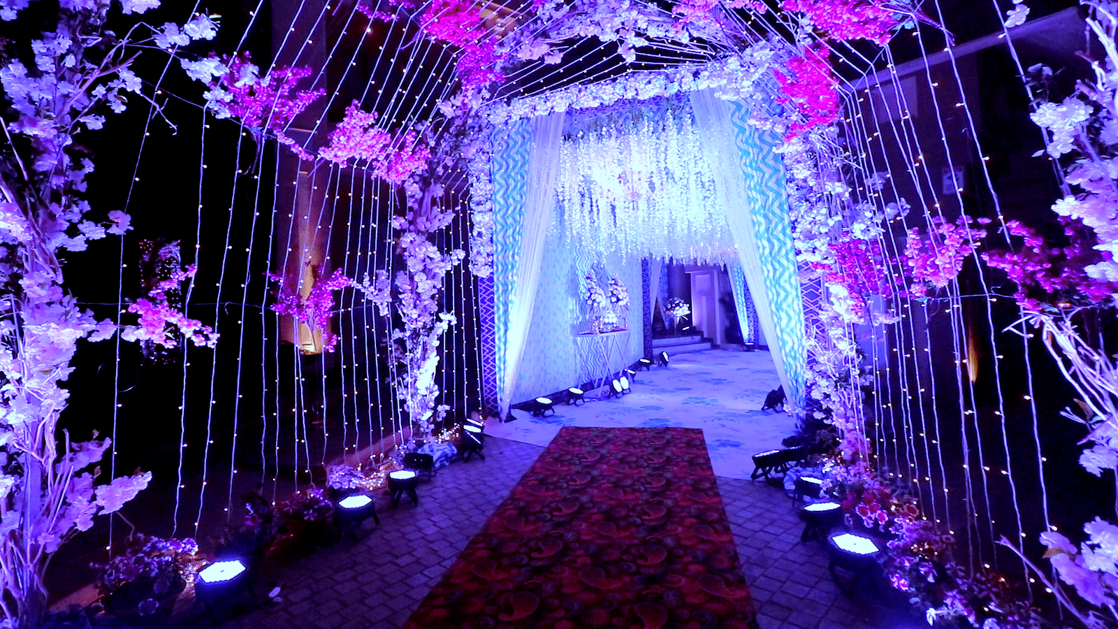 View of the banquet hall pathway decorated with flowers with purple ambient lighting at Swosti Premium Bhubhaneswar 
