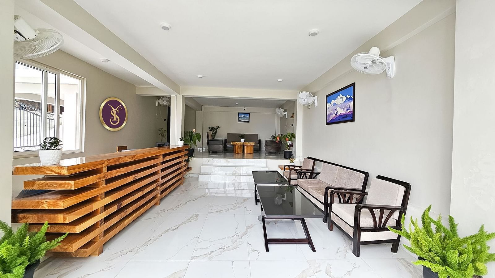 The modern and inviting lobby or reception area of Yashshree Resorts & Spa, Kalimpong, with a long wooden counter, comfortable seating, and indoor plants.