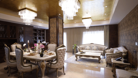 Opulent interior featuring a lavish dining area with gold-accented chairs and a classic, brightly lit chandelier.