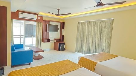 Deluxe Triple Room with a seating area, two king size beds, and a view of the outside at Yashshree Bangla Queen, Digha.