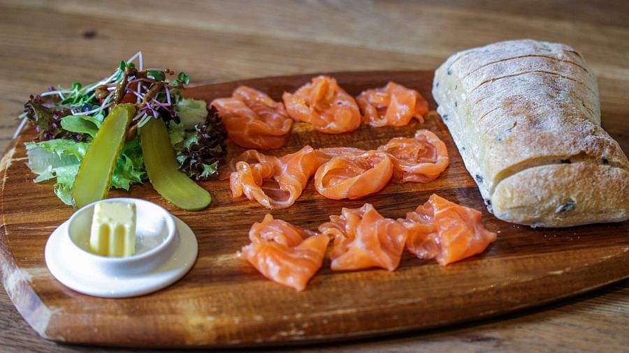 A wooden board displays smoked salmon, cream cheese, bread, and greens | The Shop | Central Mansions, Phnom Penh