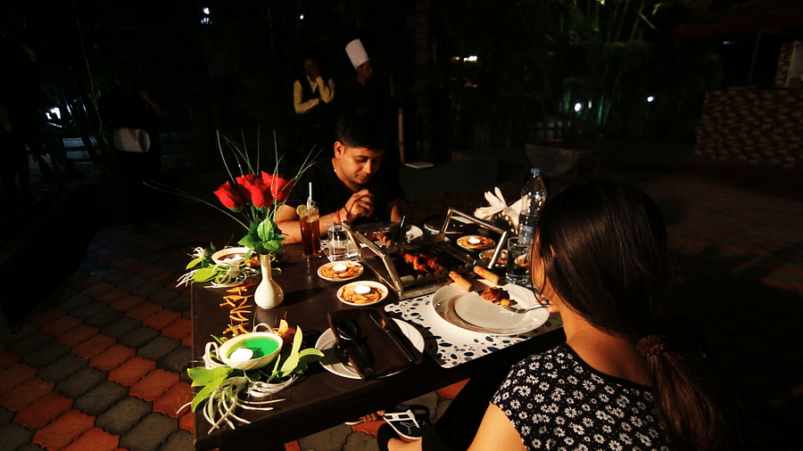 Image of two people dining with food on the table in front of them at Coorg Jungle Camp Backwater Resort, Kushalnagar.