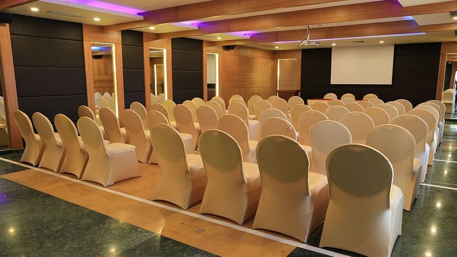 Side view of Tulip Hall at Dhanalakshmi Srinivasan Hotels, Perambalur with chairs arranged in theater style seating  and warm lighting