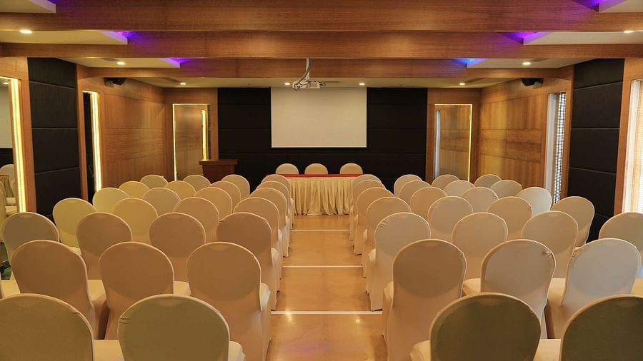 Overview of Tulip Hall at Dhanalakshmi Srinivasan Hotels, Perambalur with chairs arranged in theater style seating  and warm lighting