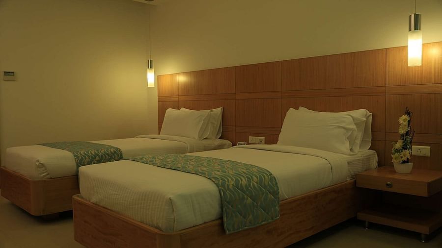 Over view of Executive Room at Dhanalakshmi Srinivasan Hotels, Perambalur featuring twin beds, furniture, and warm lighting. 