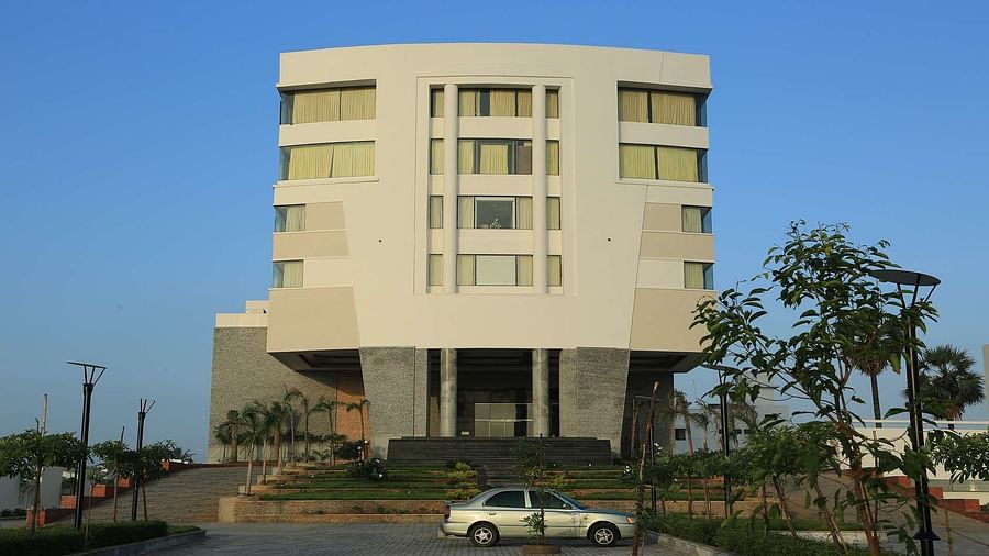 Front view of facade of Dhanalaksmi Srinivasan Hotels, Perambanur  with a backdrop of clear blue sky.