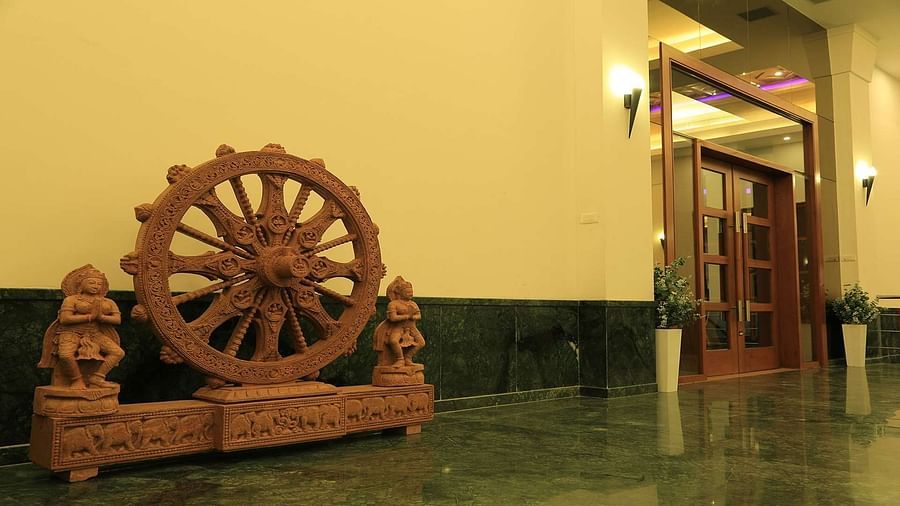 Side view of entrance door of DS Mahal Hall at Dhanalakshmi Srinivasan Hotels, Perambalur featuring a large wheel showpiece made of wood.