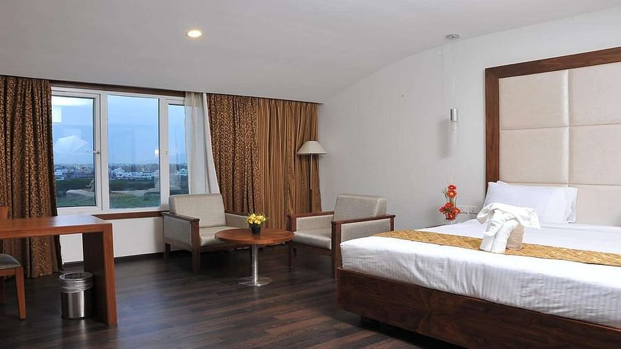 Executive Room with a king size bed, a chair, and a partially visible window at Dhanalaksmi Srinivasan Hotels, Perambalur