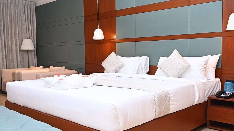 Close up of a Executive Room at Dhanalakshmi Srinivasan Hotels, Perambalur, showcasing a bed, side table, and seating area.