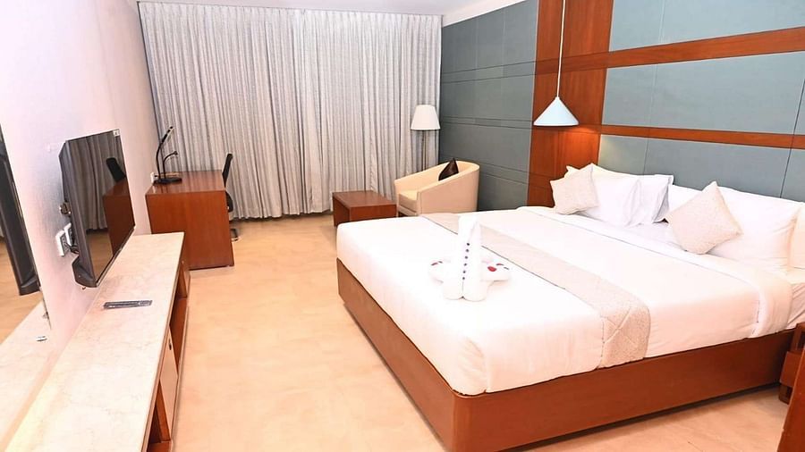 Over view of Executive Room at Dhanalakshmi Srinivasan Hotels, Perambalur featuring a king bed, furniture, and a window view. 