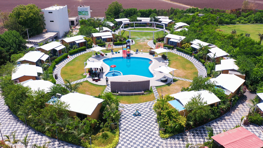 Aerial view of circular cottages surrounding pool and gardens at Lords SKD Resort, Salangpur.