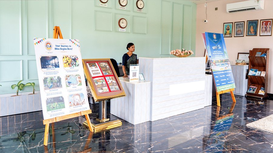 A staff member sits at the reception desk in a smart lobby, framed by information boards.