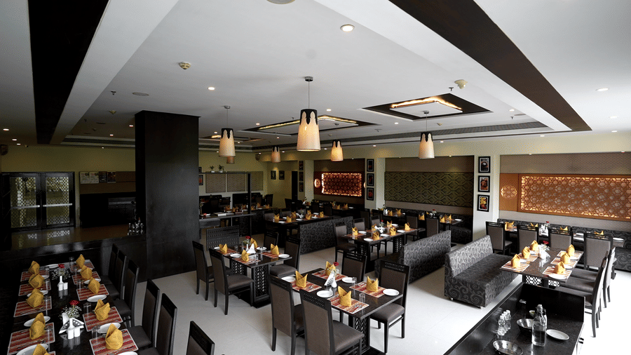 Elegant restaurant with neatly arranged tables and modern decor at Narayani Heights Hotel & Resorts, Ahmedabad.