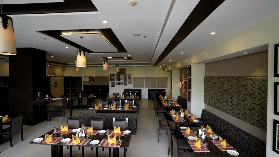 Spacious hotel restaurant with modern decor and neatly arranged tables - Narayani Heights Hotel & Resorts