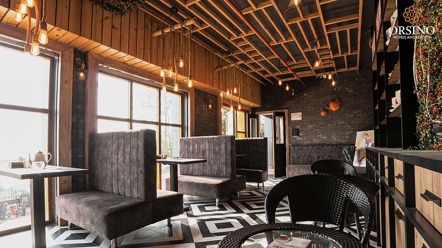 A wide shot of a cafe at Orsino Spa Resort with dark furnishings, including chairs and tables.