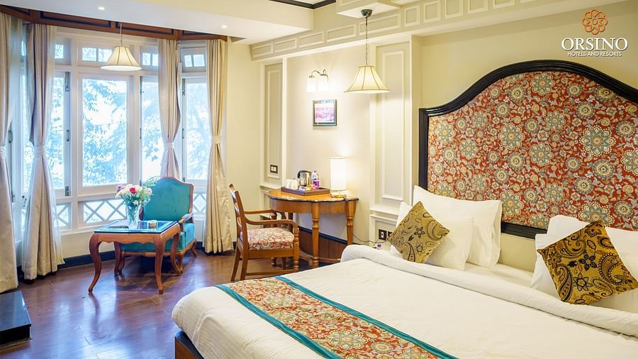 A room at Orsino Spa Resort with a large bed, a decorative headboard, and a small sitting area near a window.
