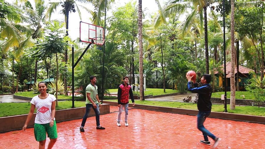 Image of four people playing basketball with trees in the background at Parampara Resort & Spa, Kushalnagar.