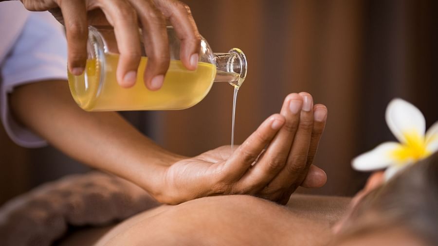 a masseur pouring oil on her hand to massage at Rhythm Gurugram