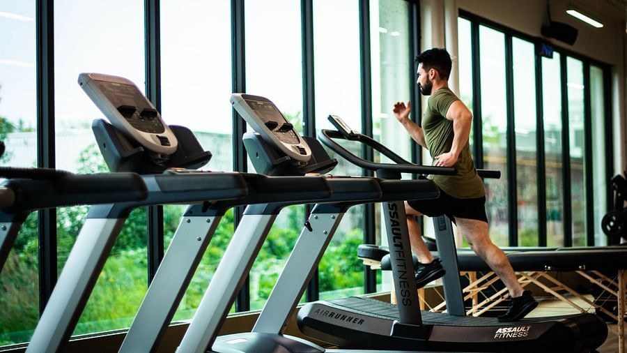 a person running on a treadmill with other treadmills next to him inside the fitness centre - Rhythm Gurugram