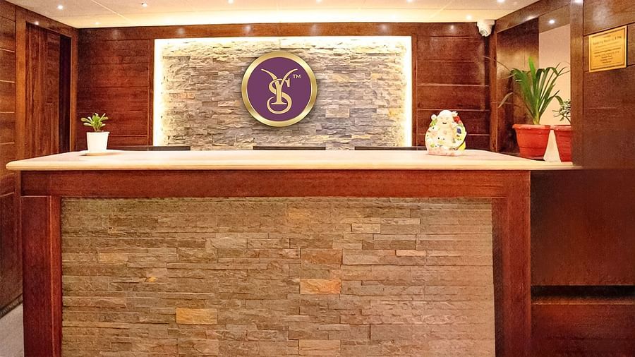 Front view shot of the reception area with the logo of Sumi Yashshree Hotels behind the desk at Sumitel, Sanderling.