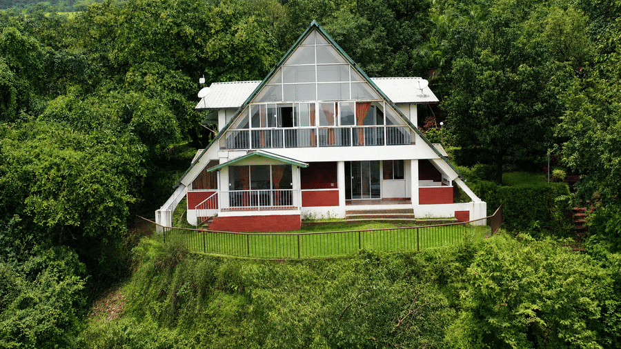 Front view of the A frame chalet at Wind Chalet, featuring large upper windows, a steeply pitched roof, and a raised garden setting.