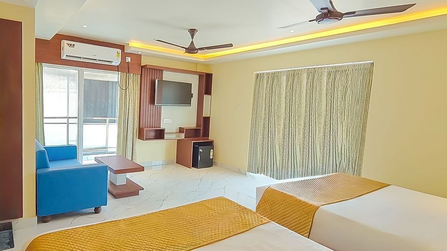Deluxe Triple Room with a seating area, two king size beds, and a view of the outside at Yashshree Bangla Queen, Digha.