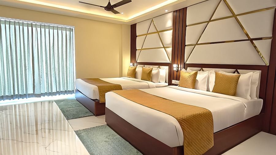Family Suite featuring two king size beds and a large window covered with curtains at Yashshree Bangla Queen, Digha.
