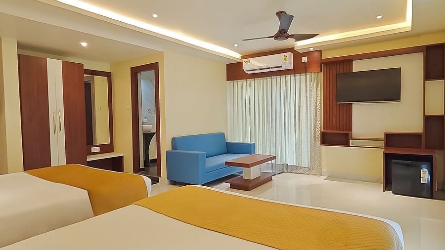 View from two large beds of a seating area, and a TV in a room at Yashshree Bangla Queen, Digha.