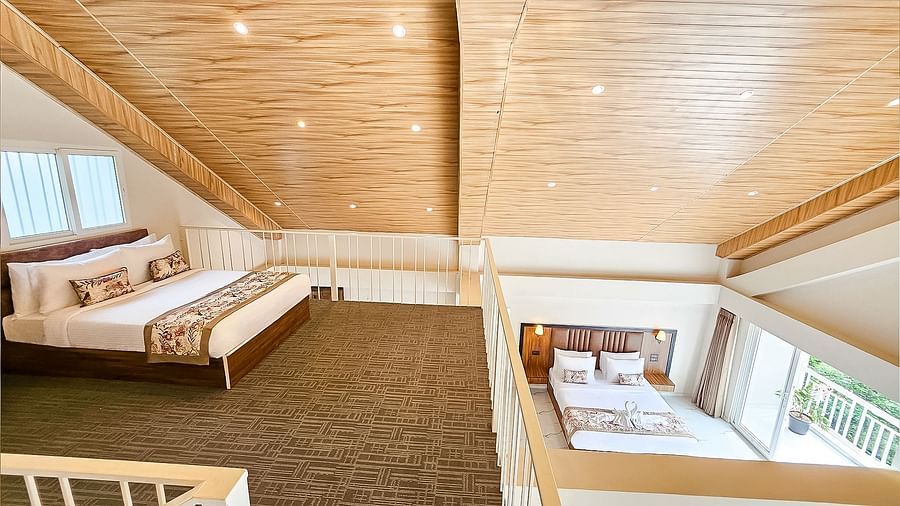 An aerial view of a bedroom space with a bed, showing the high, sloped wooden ceiling of the rooms at Yashshree Resorts & Spa, Kalimpong.