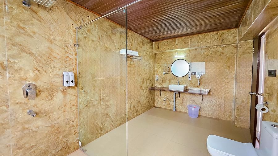 A well-appointed bathroom with a shower area, modern fixtures, and a textured wall, amenities at Yashshree Resorts & Spa, Kalimpong.