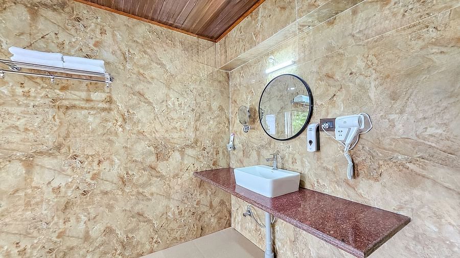 A modern bathroom with a unique textured wall, a sink, and a mirror, found within Yashshree Resorts & Spa, Kalimpong.