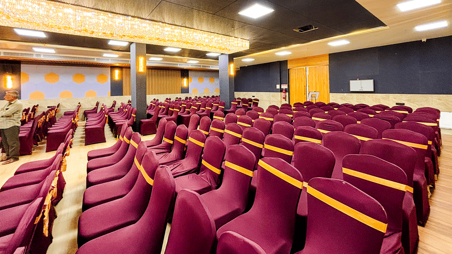 A stylish event space with armchairs and a coffee table, opening into a well-appointed bedroom.