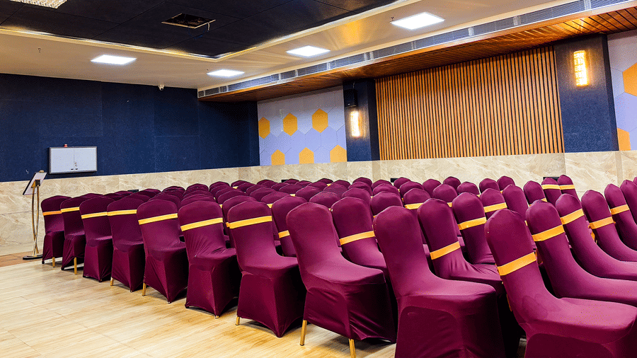 Neat rows of maroon-covered chairs featuring yellow sashes are perfectly arranged in this hall for a formal event.
