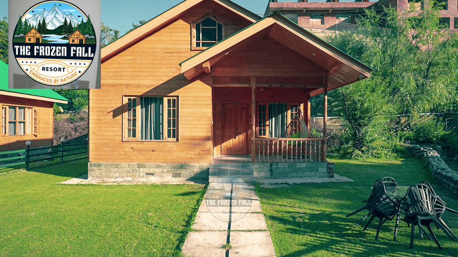 Exterior view of a wooden cottage structure at Dawat e Drung by FrozenFall Resort, Drung, Tangmarg, featuring a green lawn and a stone path.