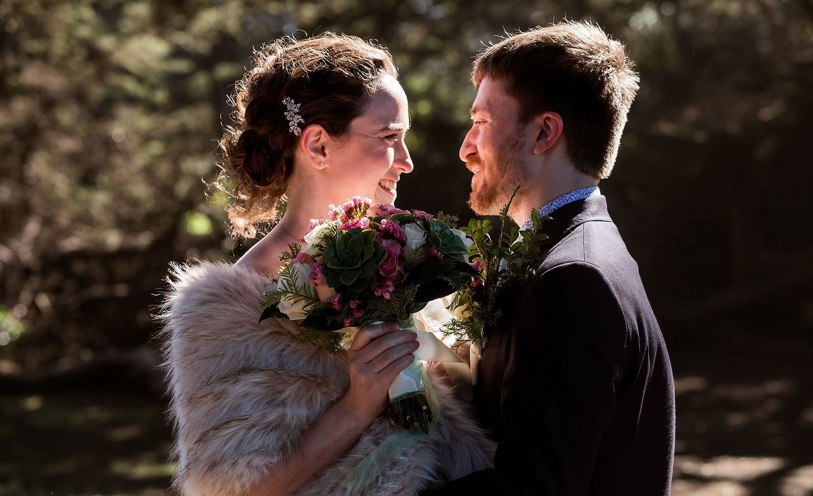 Bride in a fur stole holding a bouquet while gazing into her groom’s eyes